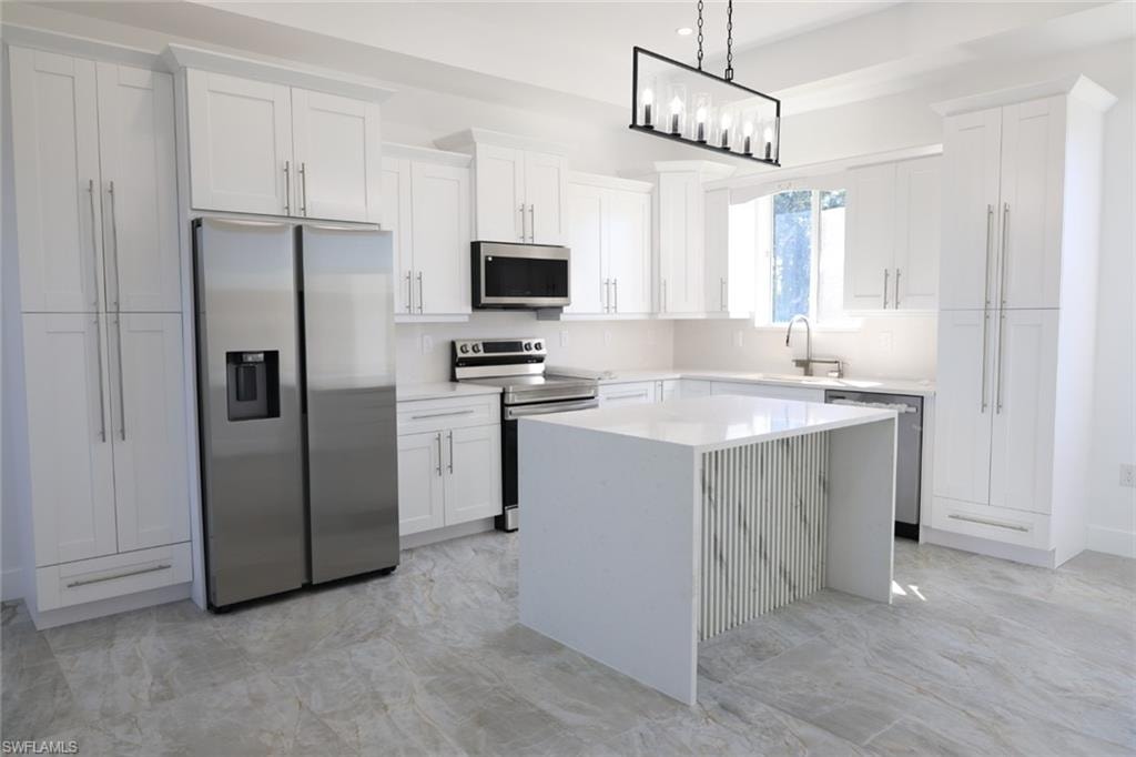 Kitchen with appliances with stainless steel finishes, a kitchen island, pendant lighting, light stone counters, and white cabinets