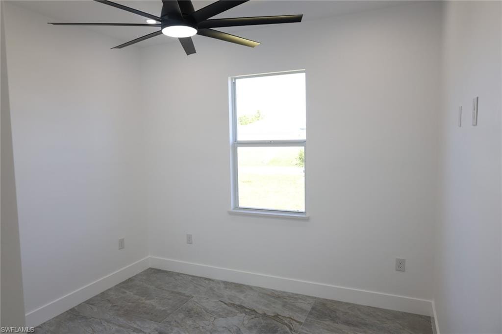 Empty room featuring baseboards and a ceiling fan
