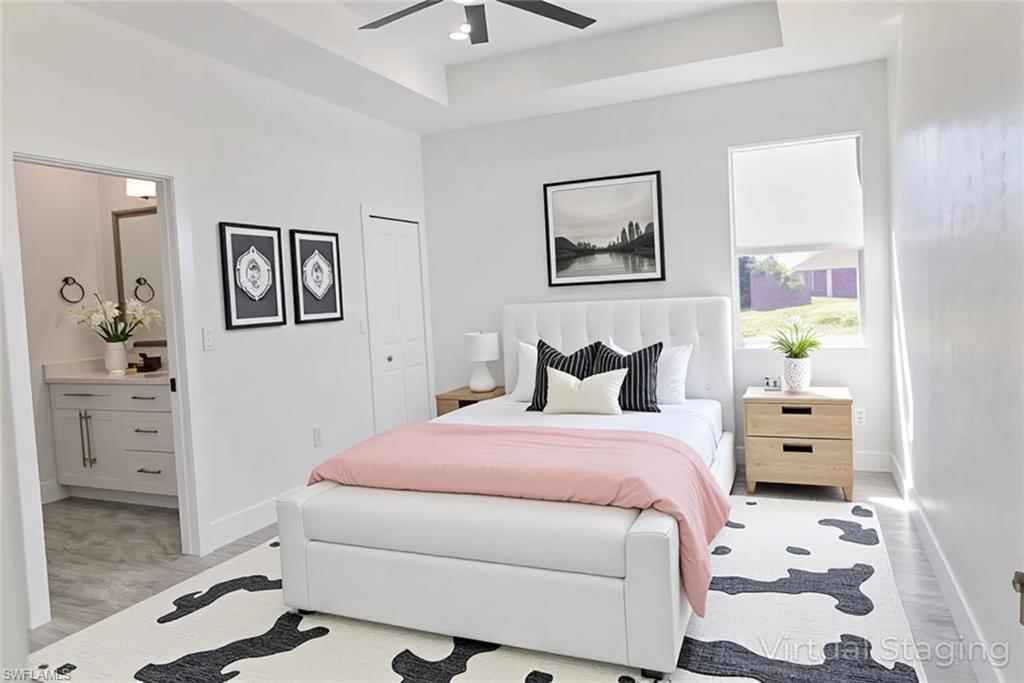 Bedroom with a raised ceiling, light wood-type flooring, ceiling fan, and a closet