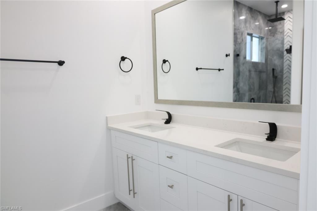 Full bath featuring a marble finish shower and double vanity