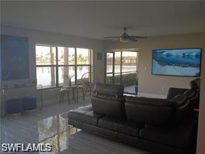 Living area with plenty of natural light, a water view, wood finished floors, and a ceiling fan