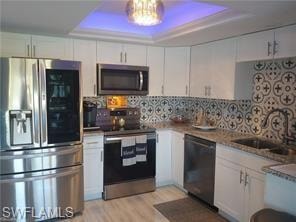 Kitchen featuring appliances with stainless steel finishes, white cabinetry, and a raised ceiling