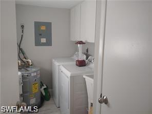 Laundry area featuring independent washer and dryer, cabinet space, and electric panel