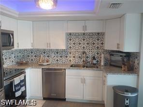 Kitchen with white cabinetry, appliances with stainless steel finishes, and backsplash