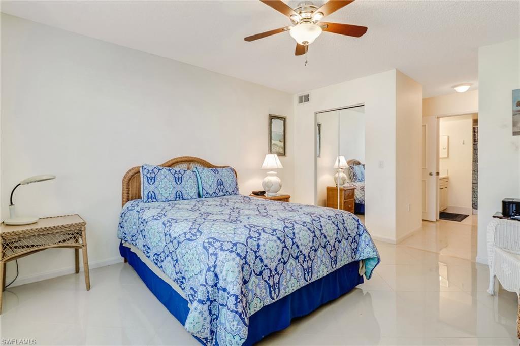 Bedroom with light tile patterned floors, a closet, ceiling fan, and ensuite bath