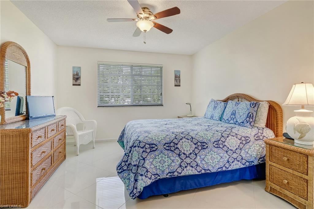 Tiled bedroom with ceiling fan and a textured ceiling