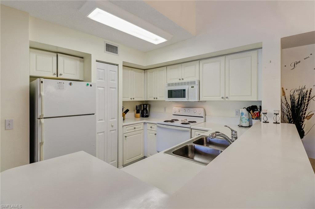 Kitchen with white appliances, light countertops, and white cabinetry