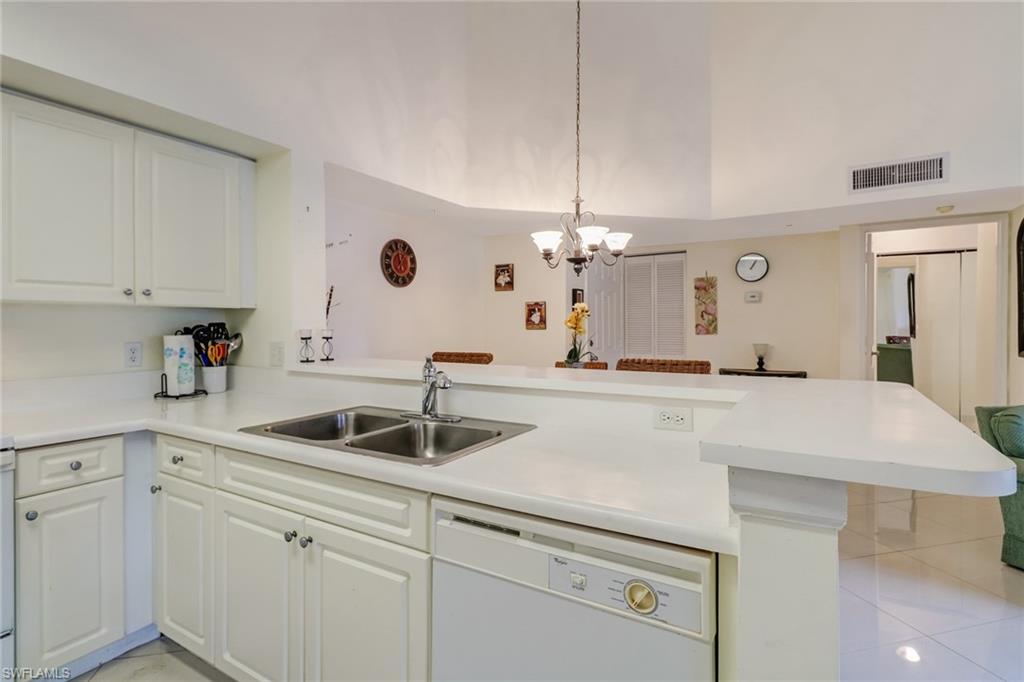 Kitchen with light countertops, dishwasher, pendant lighting, white cabinetry, and a peninsula