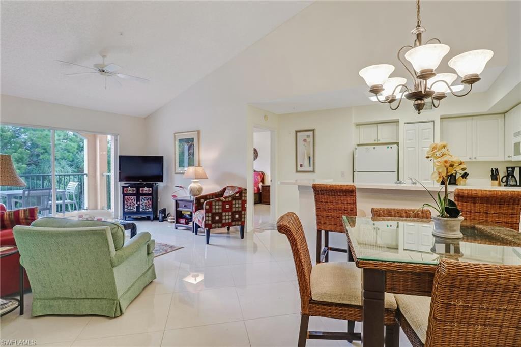 Dining area featuring light tile patterned floors, high vaulted ceiling, a chandelier, and ceiling fan