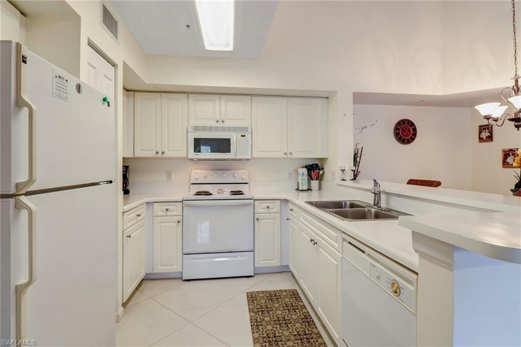 Kitchen featuring white appliances, light countertops, light tile patterned floors, and white cabinets