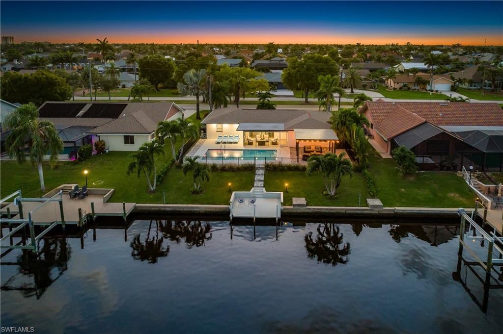 Aerial view at dusk of a water view, a residential view, and view of pool area