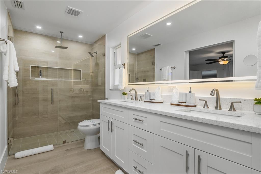 Full bathroom with a stall shower, double vanity, recessed lighting, and wood tiled floors