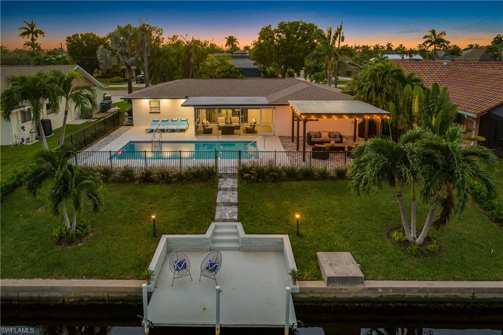 Back of house at dusk with an outdoor hangout area, a patio, a fenced backyard, and a water view