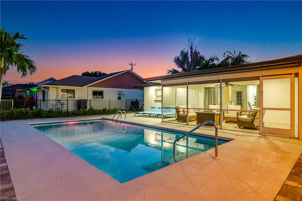 Pool at dusk with ceiling fan, an outdoor living space, and a patio area