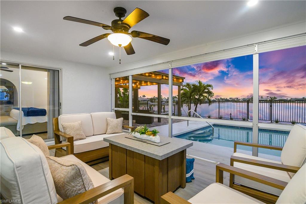 Pool at dusk featuring a water view and ceiling fan