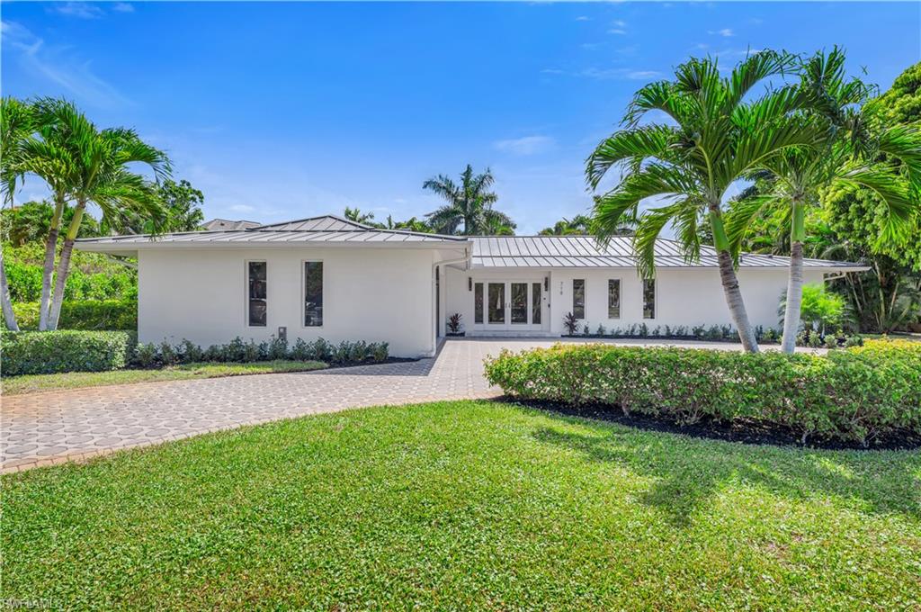 Ranch-style house with stucco siding, a front lawn, a standing seam roof, and a metal roof