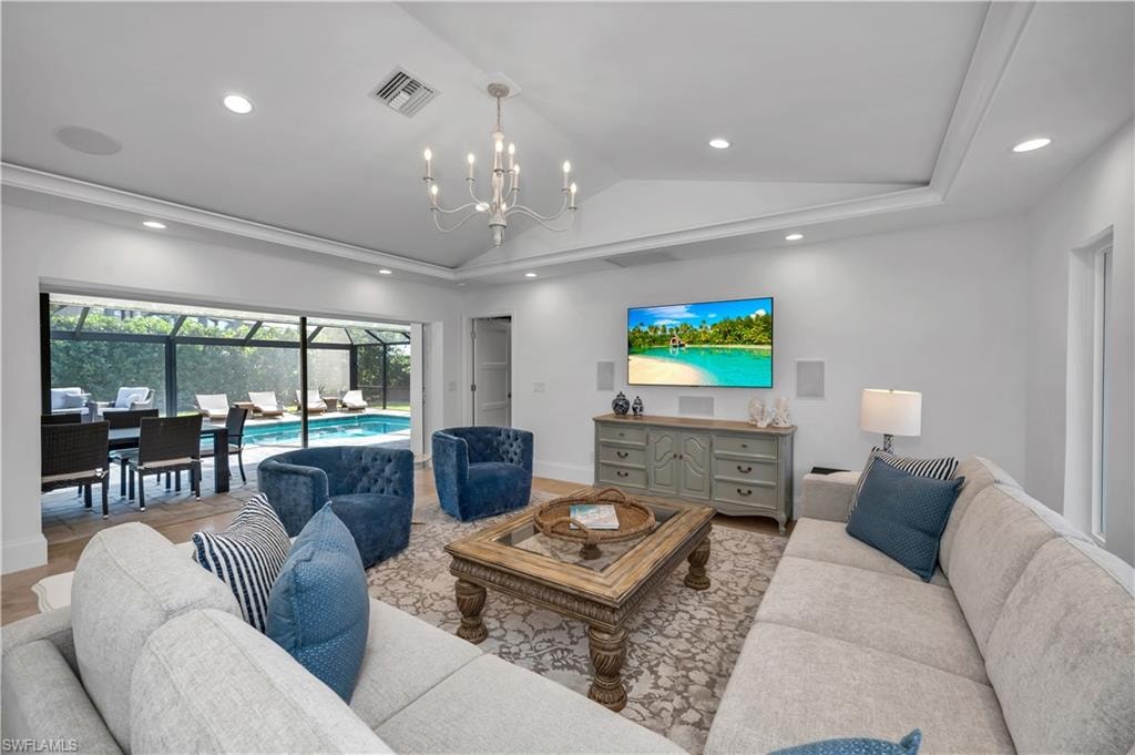 Living room with vaulted ceiling, recessed lighting, light wood-style floors, and a chandelier