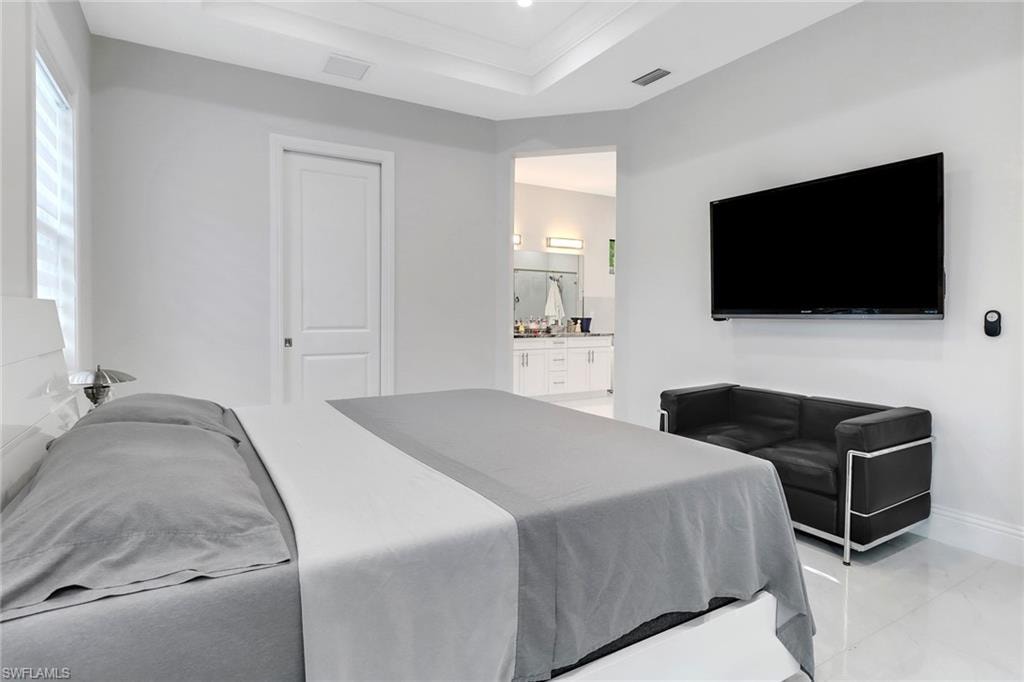 Bedroom with connected bathroom, a raised ceiling, light tile patterned floors, and recessed lighting
