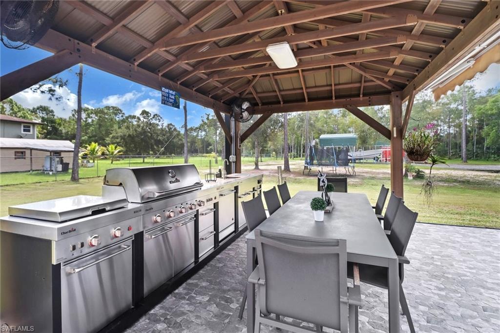 View of patio / terrace featuring a trampoline, outdoor dining space, and an outdoor kitchen