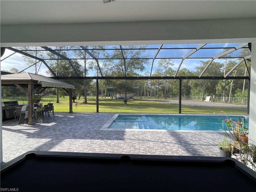 Swimming pool with a lawn, a patio area, and screen enclosure