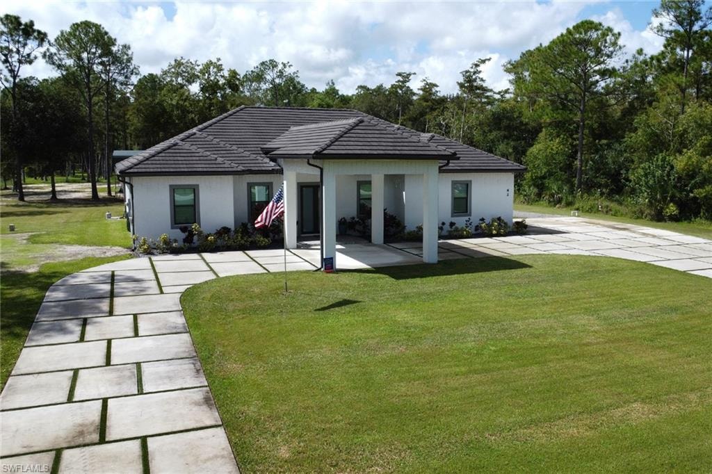 view of house with a yard, a tiled roof, and stucco siding