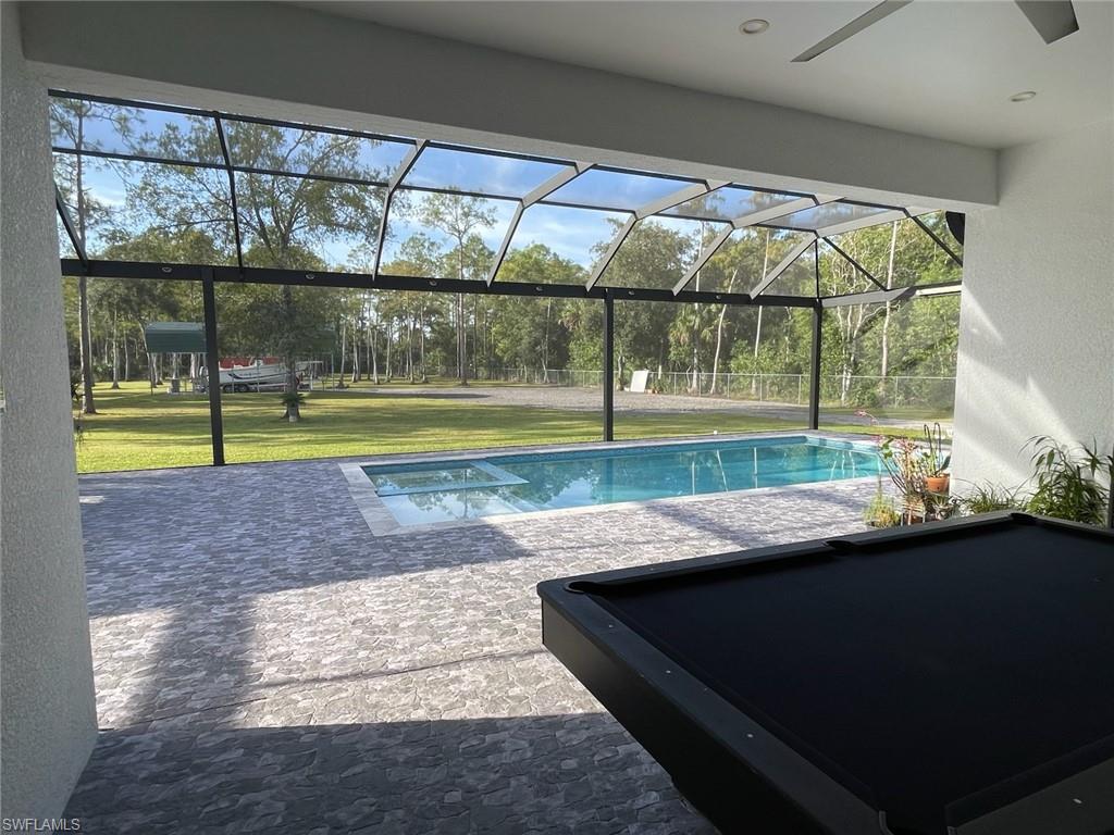 Outdoor pool with screen enclosure, a patio area, and a lawn