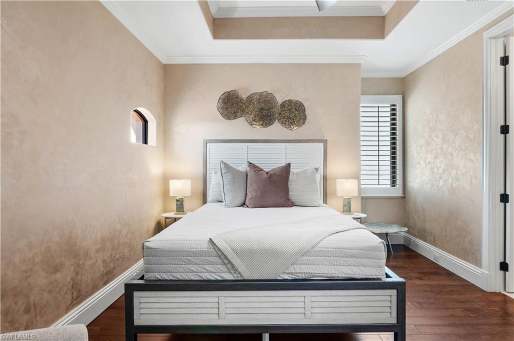Bedroom featuring dark wood-style flooring, ornamental molding, and a raised ceiling