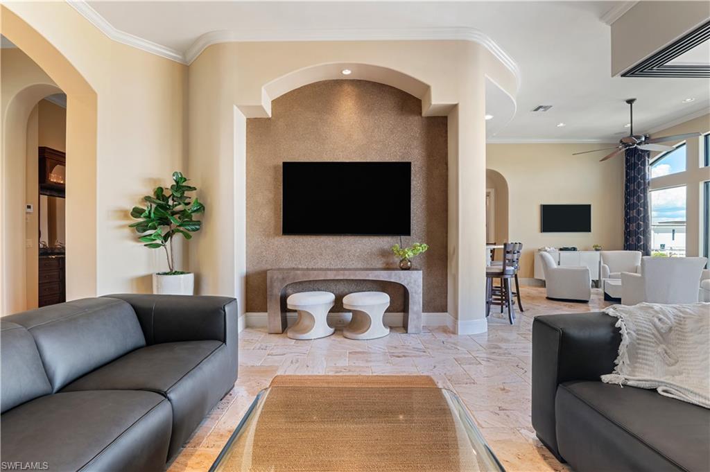 Living room with arched walkways, crown molding, ceiling fan, and recessed lighting