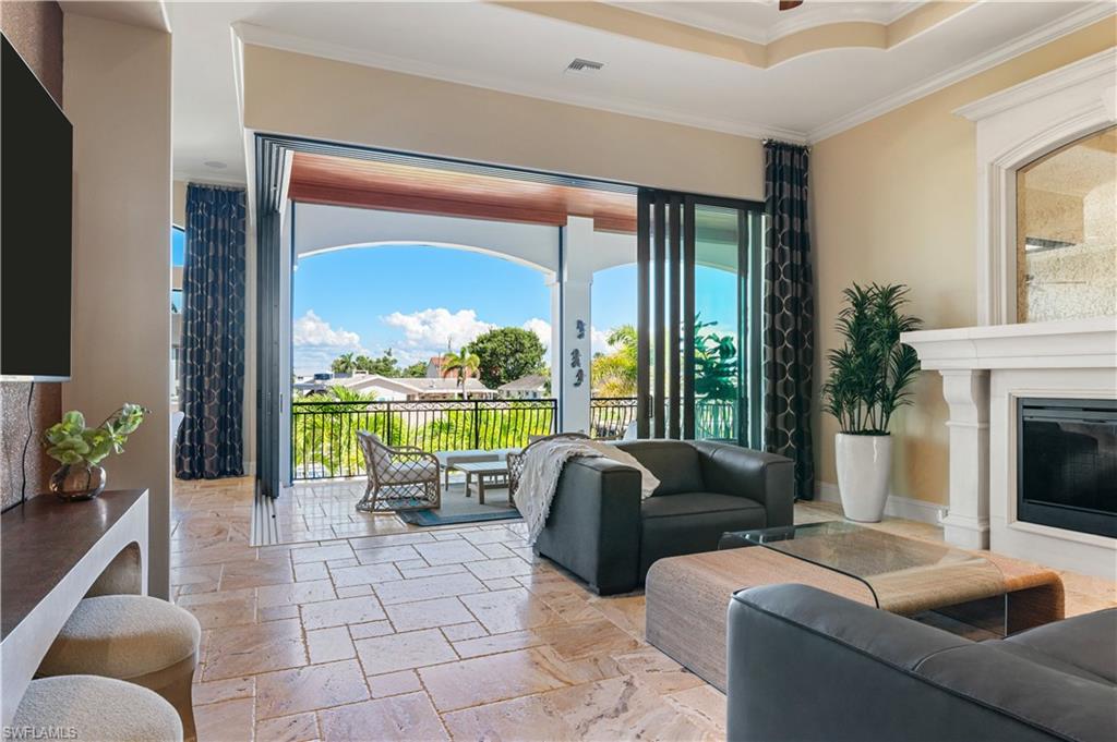 Living area featuring ornamental molding, stone tile flooring, and a glass covered fireplace