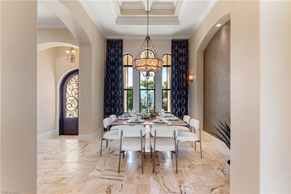 Dining space featuring a chandelier, crown molding, light marble finish floors, a towering ceiling, and arched walkways