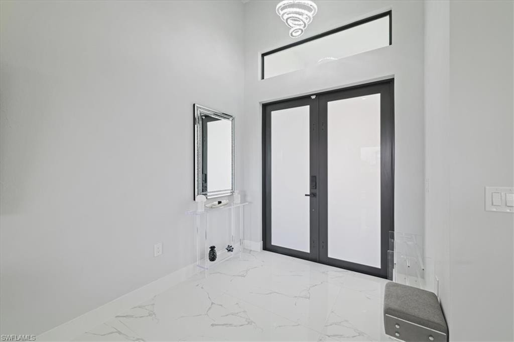 Entrance foyer featuring marble tiled flooring, french doors, and a towering ceiling