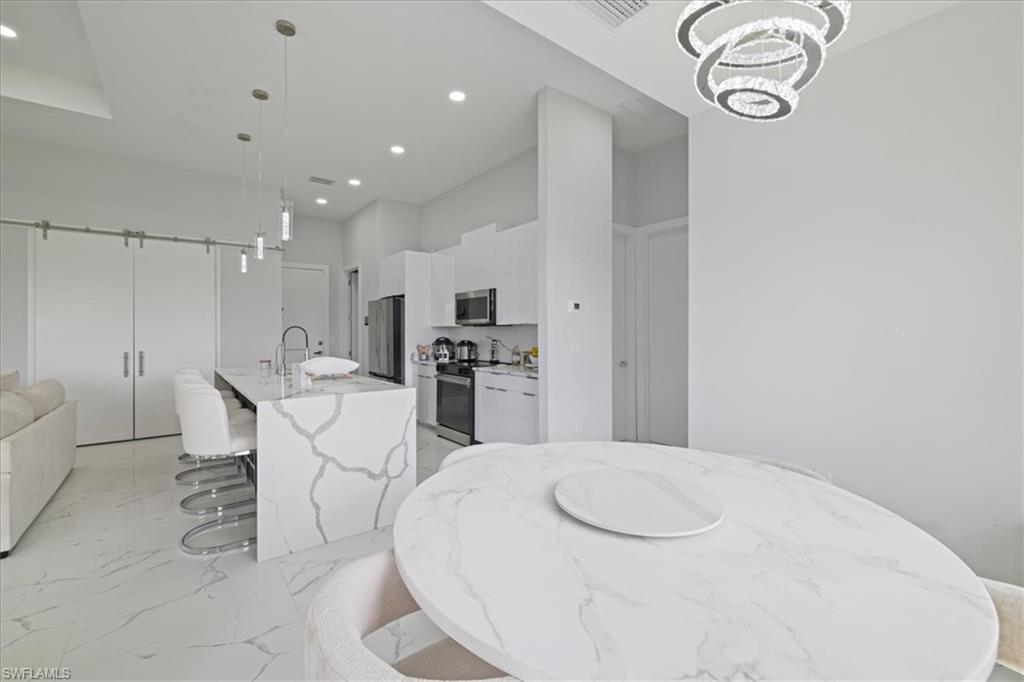 Kitchen with pendant lighting, an island with sink, a breakfast bar, open floor plan, and modern cabinets