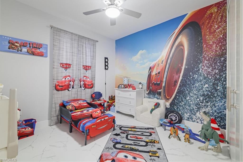 Rec room with light marble finish floors and ceiling fan