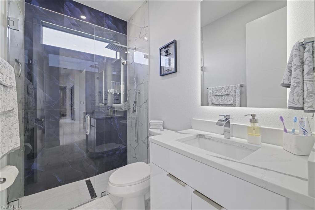 Bathroom featuring vanity, a marble finish shower, and a textured wall
