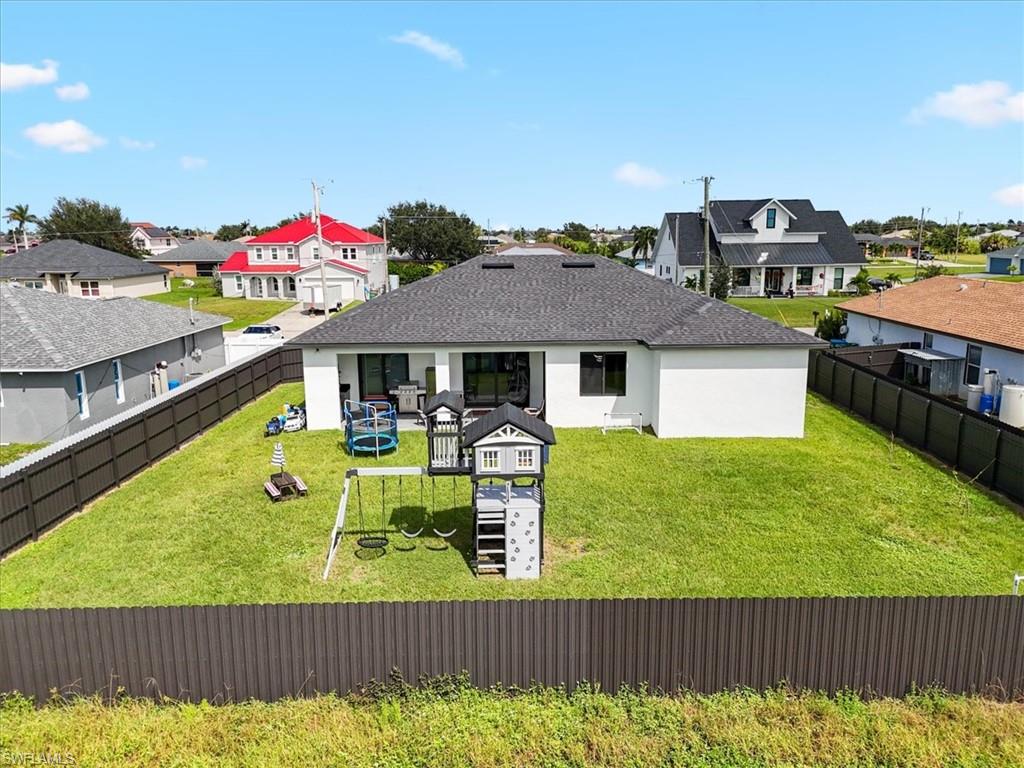 View of front of property with a residential view, roof with shingles, a patio, a fenced backyard, and stucco siding