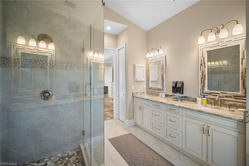 Bathroom featuring double vanity, a stall shower, light tile patterned flooring, and recessed lighting