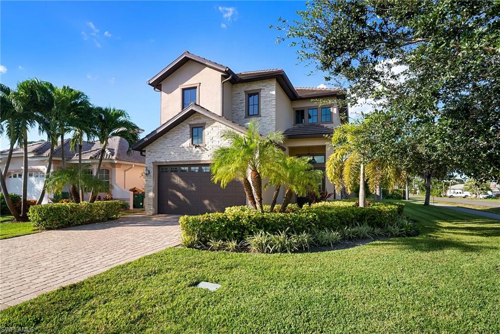 View of front of home featuring stone siding, stucco siding, decorative driveway, and a front lawn