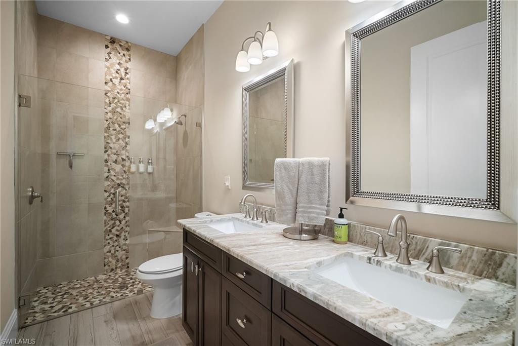 Bathroom featuring double vanity, a stall shower, and light wood-style floors