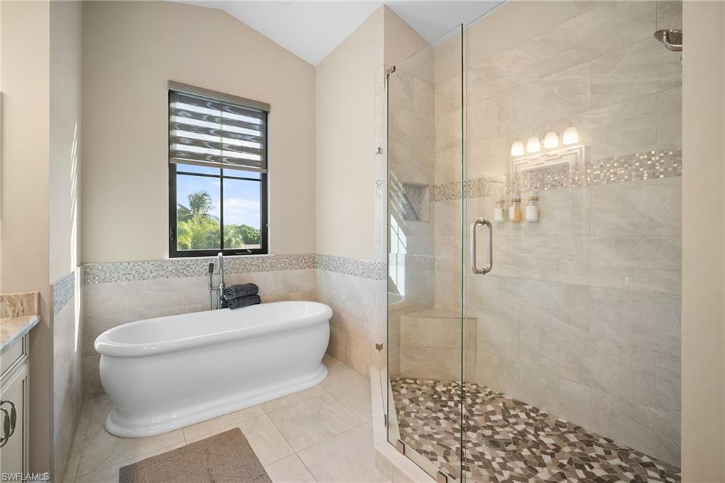 Bathroom featuring vanity, tile walls, a freestanding tub, a wainscoted wall, and a stall shower