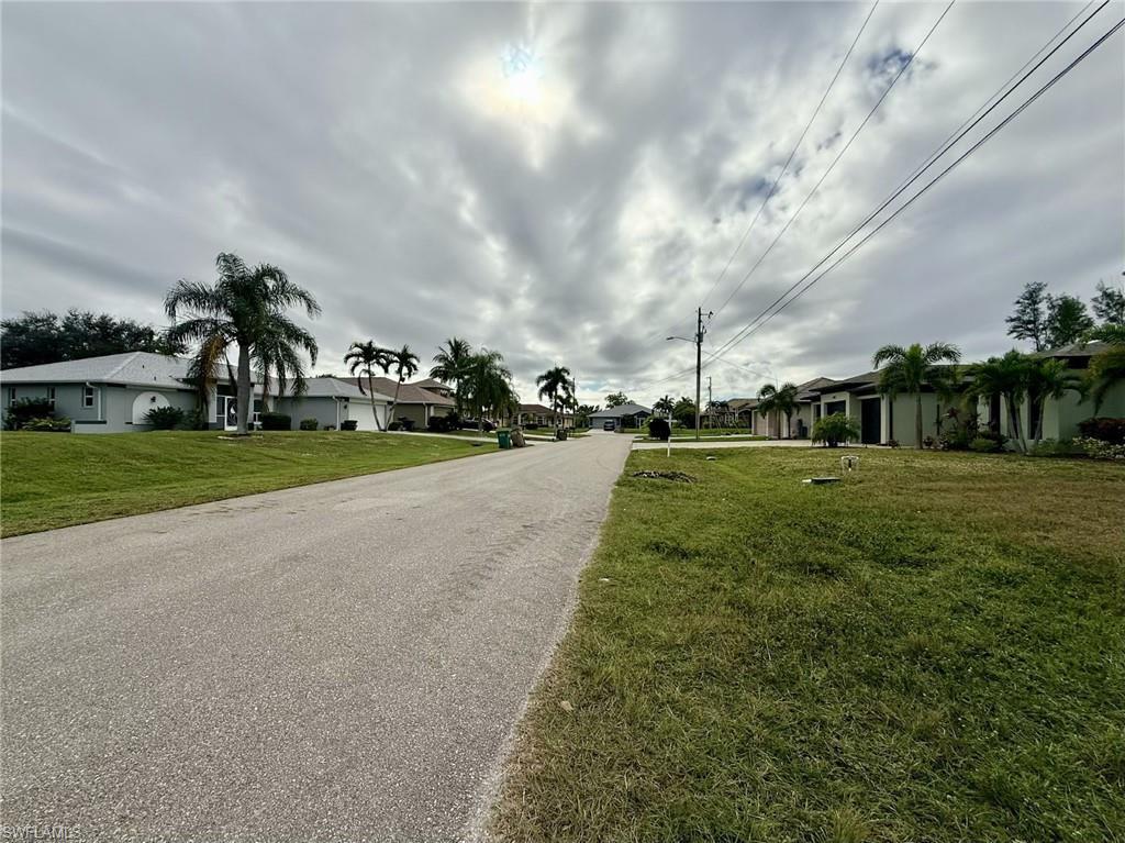View of asphalt street featuring a residential view and street lights