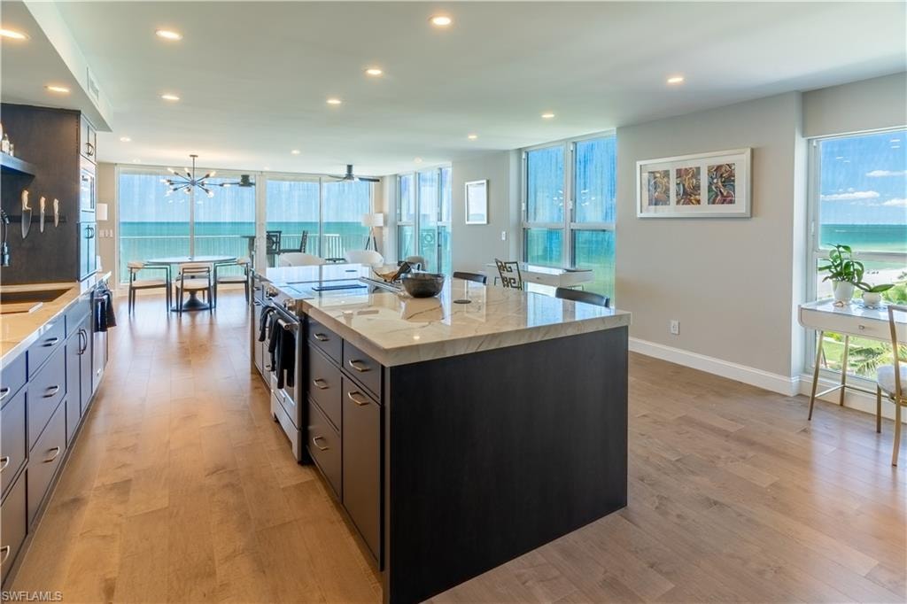 Kitchen featuring light stone counters, stainless steel electric stove, a spacious island, light wood-style flooring, and recessed lighting
