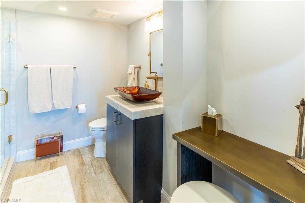 Full bath with vanity, light wood-type flooring, and a stall shower
