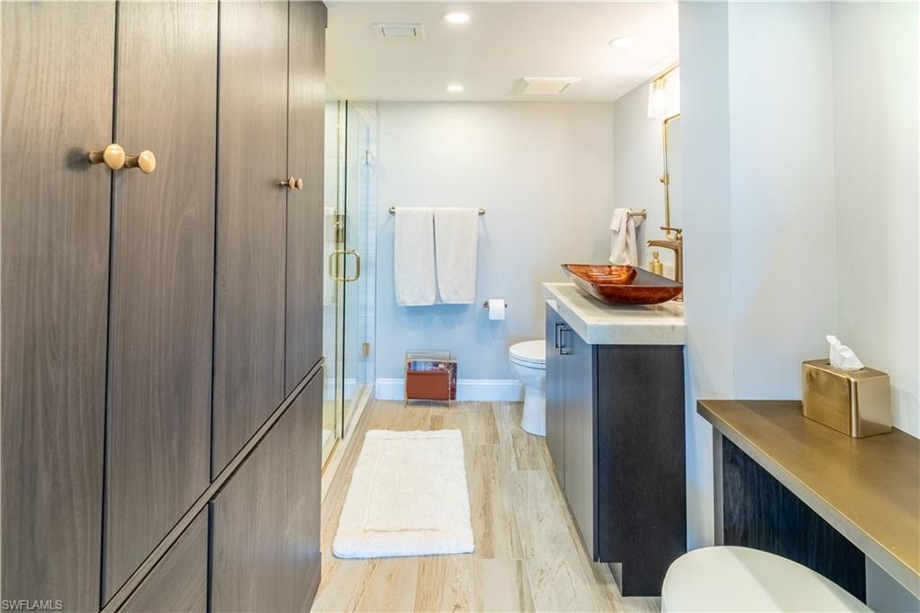 Bathroom with light wood-style floors, a stall shower, vanity, and recessed lighting