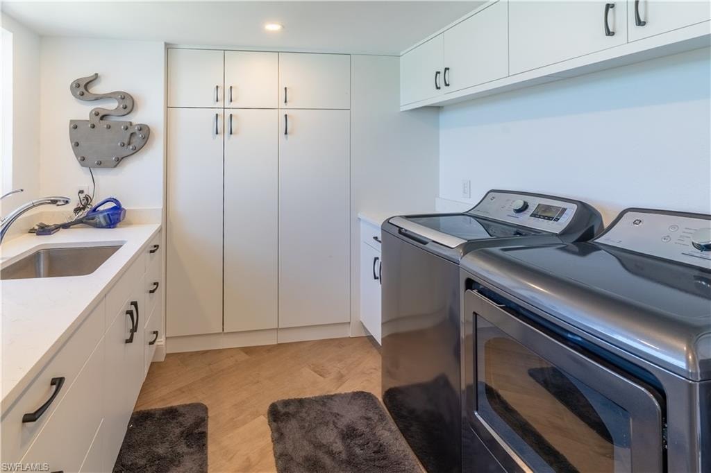 Laundry area with cabinet space, washer and clothes dryer, and recessed lighting