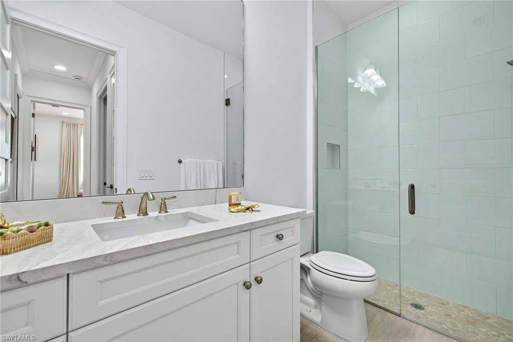Bathroom featuring a shower stall, vanity, and light wood-style flooring
