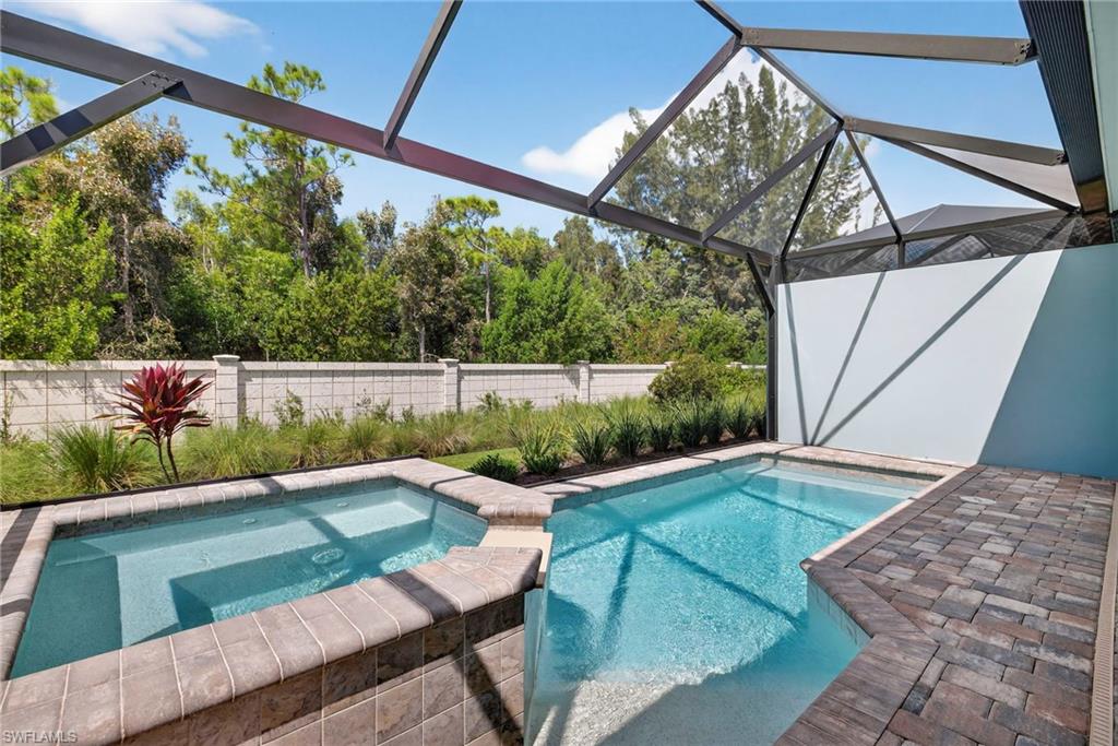View of swimming pool with a sunroom, a patio, glass enclosure, a fenced backyard, and a pool with connected hot tub