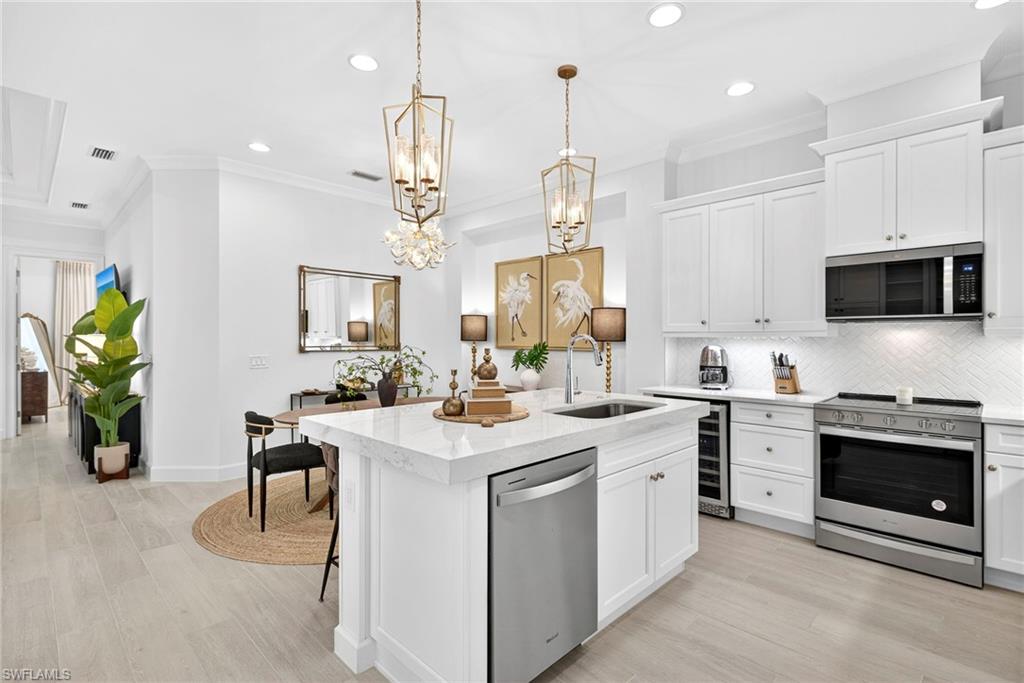 Kitchen with crown molding, recessed lighting, white cabinets, stainless steel appliances, and decorative backsplash
