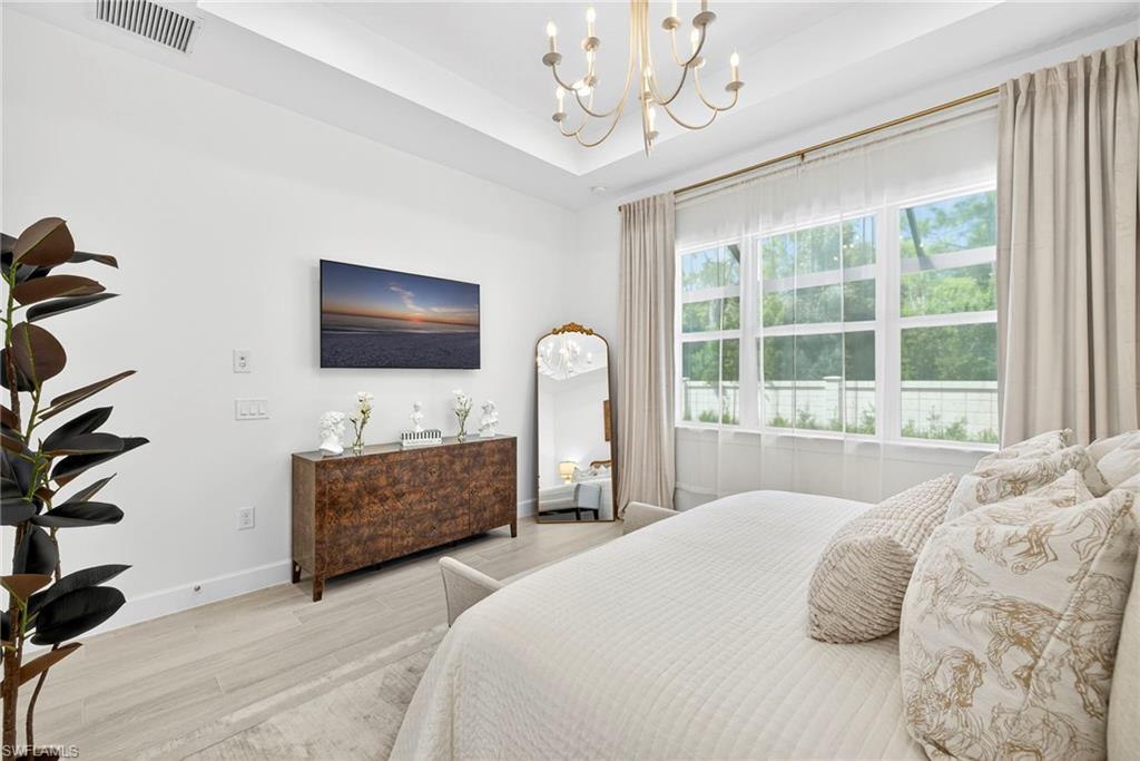 Bedroom with a chandelier, wood finished floors, and a raised ceiling