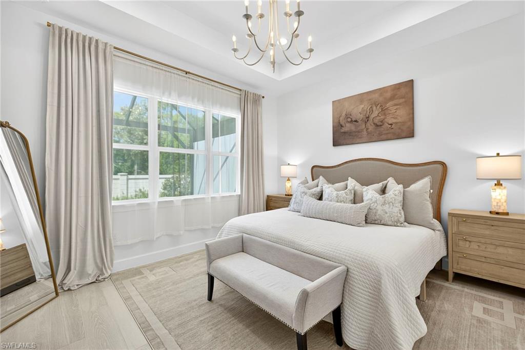 Bedroom with wood finished floors, a chandelier, and a tray ceiling