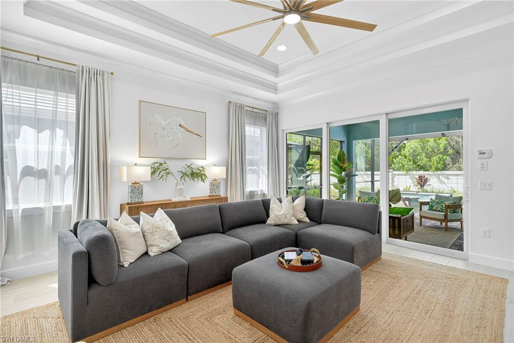 Living area with a tray ceiling, recessed lighting, crown molding, wood finished floors, and a ceiling fan